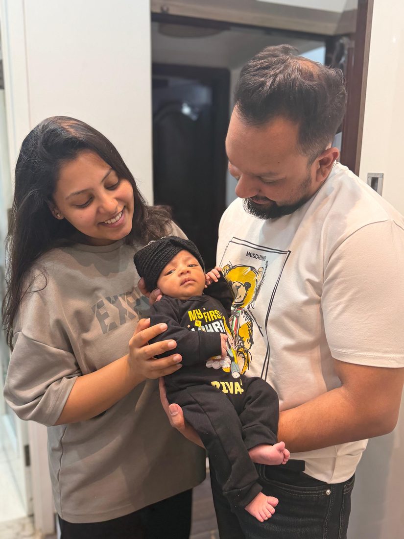 Mum and dad holding Rivaay in a beanie, smiling down at him